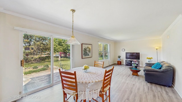 dining area with light wood-style floors, crown molding, and baseboards
