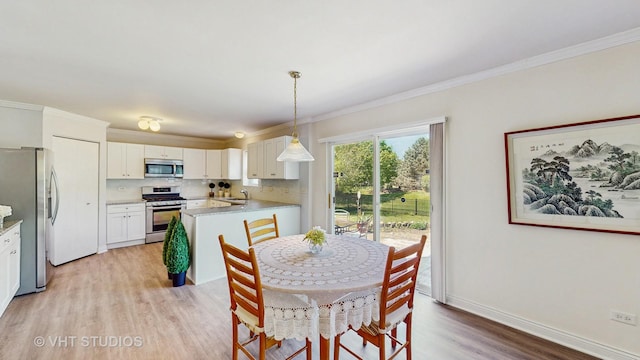 dining room featuring light wood-type flooring, ornamental molding, and baseboards