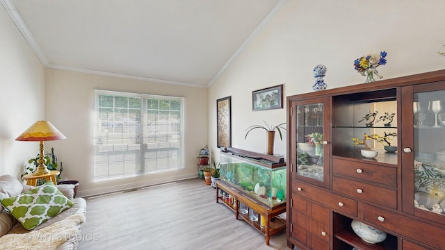 interior space with lofted ceiling, crown molding, light wood finished floors, and baseboards