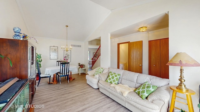 living area featuring lofted ceiling, stairway, a chandelier, light wood-style flooring, and crown molding