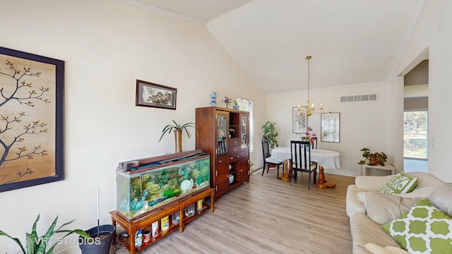 living area with a chandelier, vaulted ceiling, light wood-style floors, ornamental molding, and baseboards