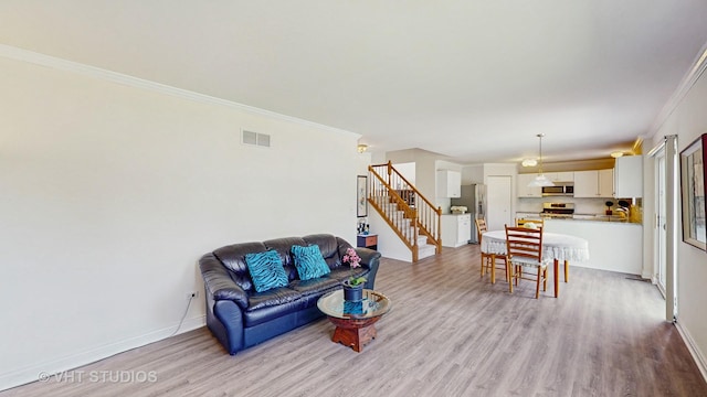 living area with stairs, light wood-type flooring, crown molding, and baseboards