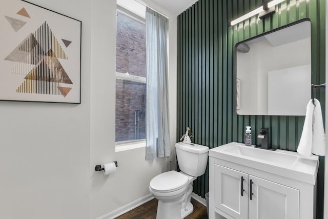bathroom featuring baseboards, wood finished floors, toilet, and healthy amount of natural light