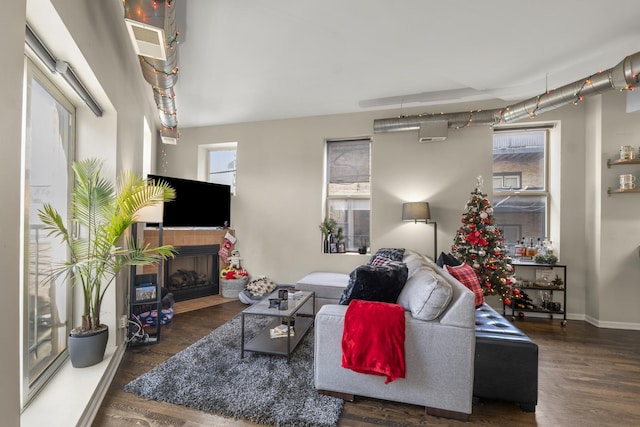 living area with wood finished floors, plenty of natural light, a fireplace, and baseboards