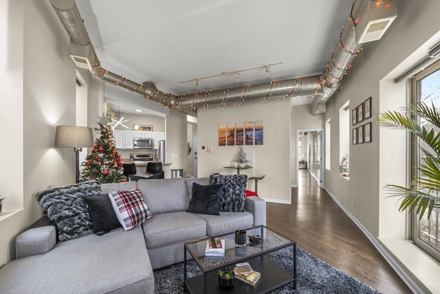 living room featuring dark wood-type flooring, baseboards, and track lighting