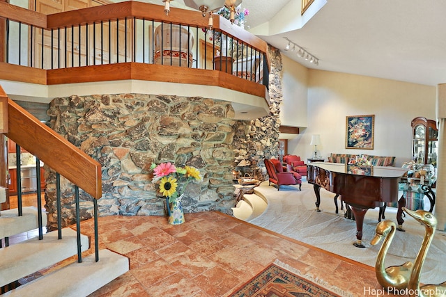 staircase with track lighting, a towering ceiling, and stone finish floors