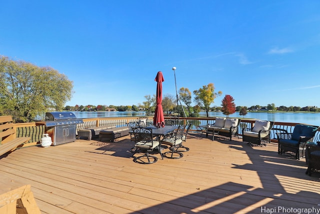 deck with outdoor lounge area, a water view, and grilling area