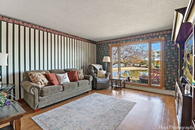 living area featuring wallpapered walls, baseboard heating, a textured ceiling, a water view, and wood finished floors