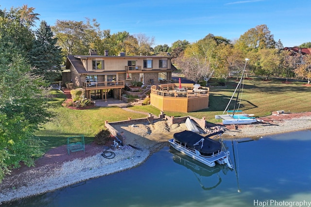 rear view of house with a yard and a deck with water view