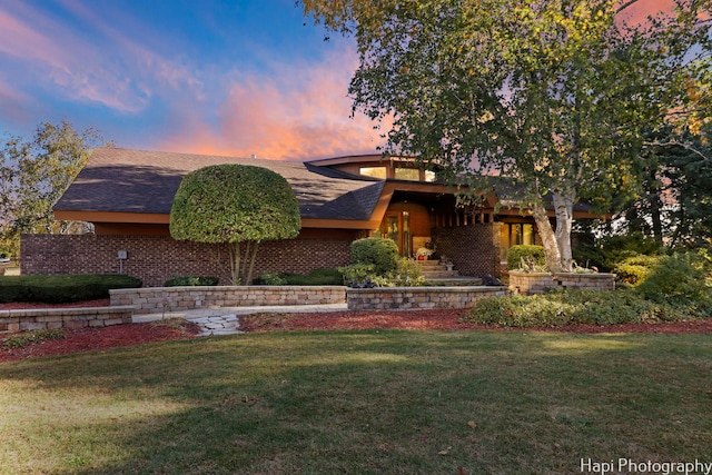 view of front of property with a lawn and a shingled roof