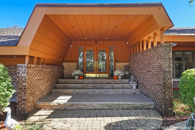 doorway to property with french doors, brick siding, board and batten siding, and stone siding