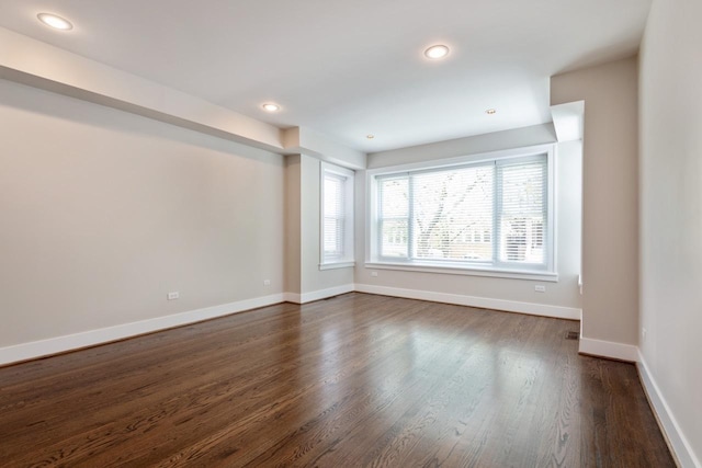 spare room with baseboards, dark wood-style floors, and recessed lighting