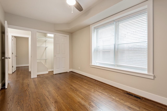 unfurnished bedroom with a closet, visible vents, dark wood finished floors, ceiling fan, and baseboards