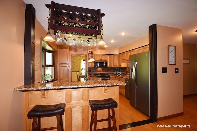 5N850 Ravine Dr, Saint Charles, IL 60175 - kitchen featuring appliances with stainless steel finishes, a sink, light wood finished floors, light stone countertops, and a peninsula