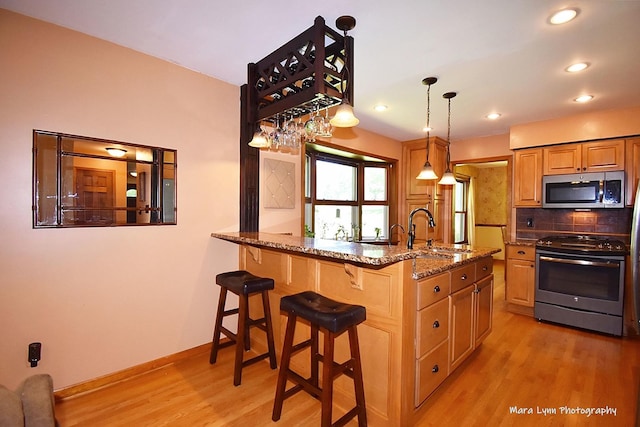 5N850 Ravine Dr, Saint Charles, IL 60175 - kitchen featuring appliances with stainless steel finishes, light wood-type flooring, a sink, stone countertops, and a kitchen breakfast bar