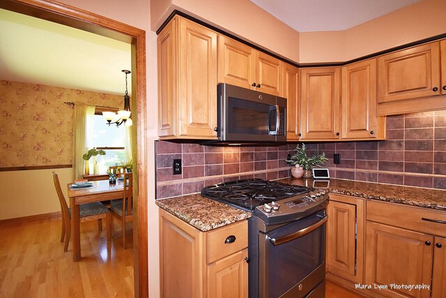 5N850 Ravine Dr, Saint Charles, IL 60175 - kitchen with stainless steel gas range, a chandelier, light wood-style flooring, dark stone counters, and wainscoting