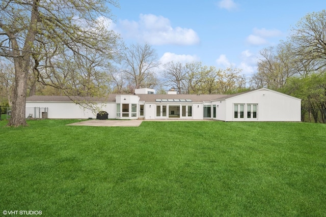 rear view of property with french doors, a patio, a lawn, and stucco siding