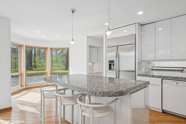 kitchen with dishwasher, stainless steel built in fridge, white cabinets, modern cabinets, and a kitchen bar