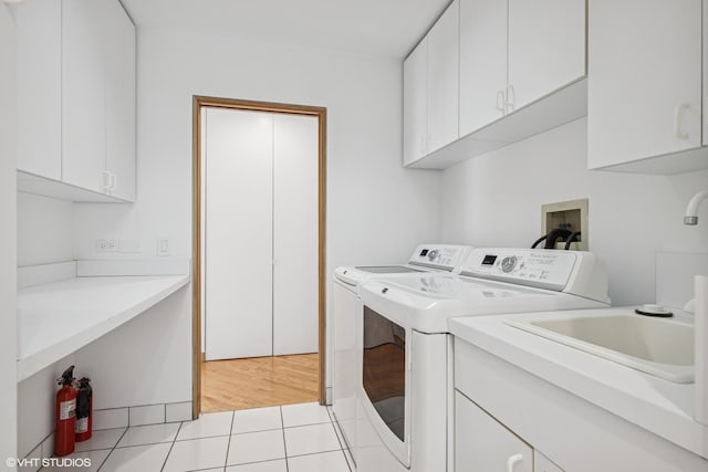 washroom with cabinet space, washing machine and dryer, and light tile patterned floors