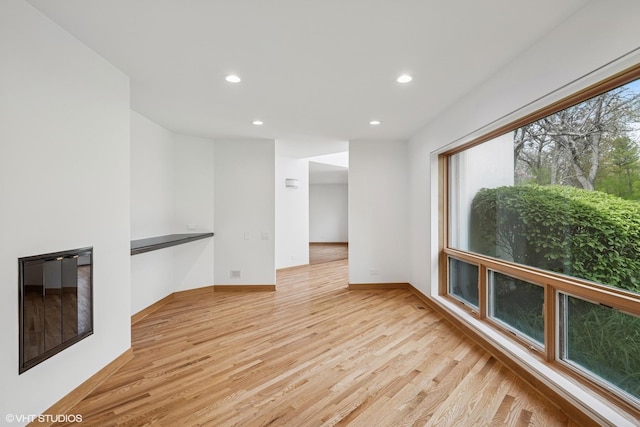unfurnished living room featuring light wood finished floors, recessed lighting, and baseboards