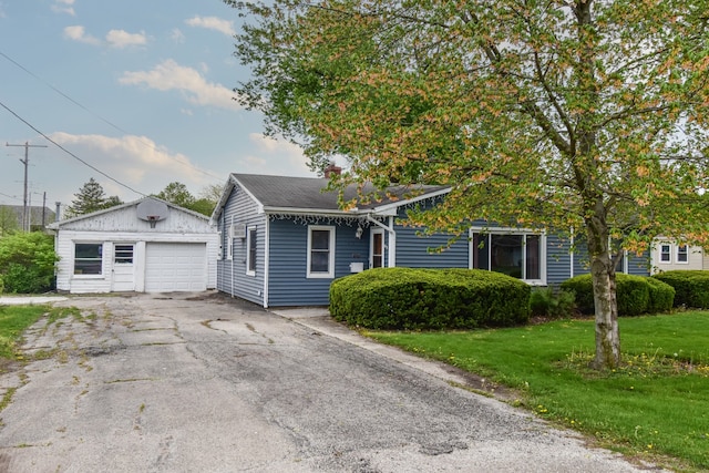 view of front facade with a garage, an outbuilding, driveway, and a front lawn