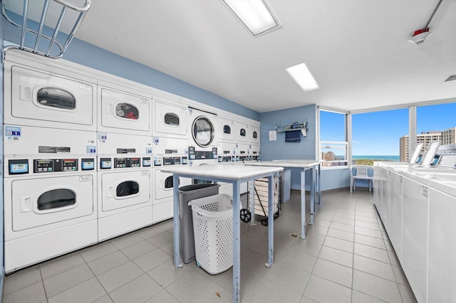 community laundry room with estacked washer and dryer, independent washer and dryer, and light tile patterned floors