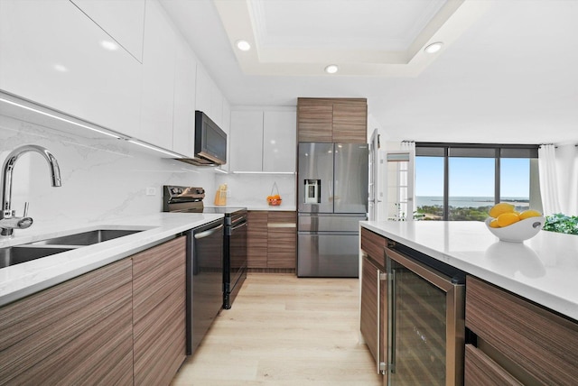 kitchen with a sink, stainless steel appliances, wine cooler, recessed lighting, and light wood-style flooring