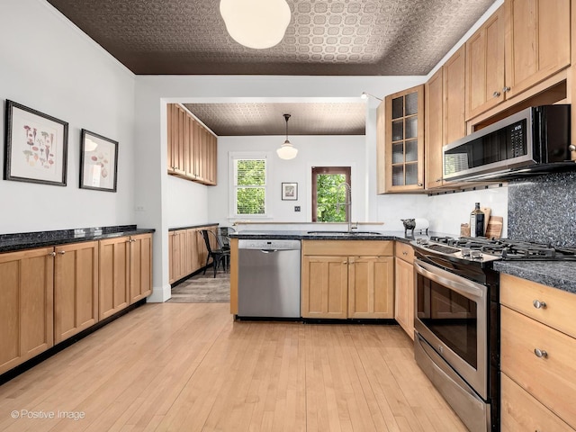 213 S Ashland Ave, La Grange, IL 60525 - kitchen with stainless steel appliances, a sink, a peninsula, dark countertops, and light wood-style flooring