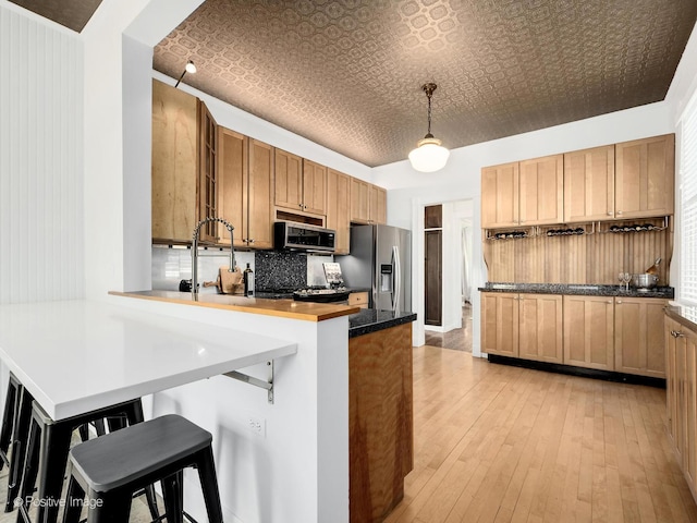 213 S Ashland Ave, La Grange, IL 60525 - kitchen featuring appliances with stainless steel finishes, an ornate ceiling, a peninsula, a breakfast bar, and light wood-type flooring