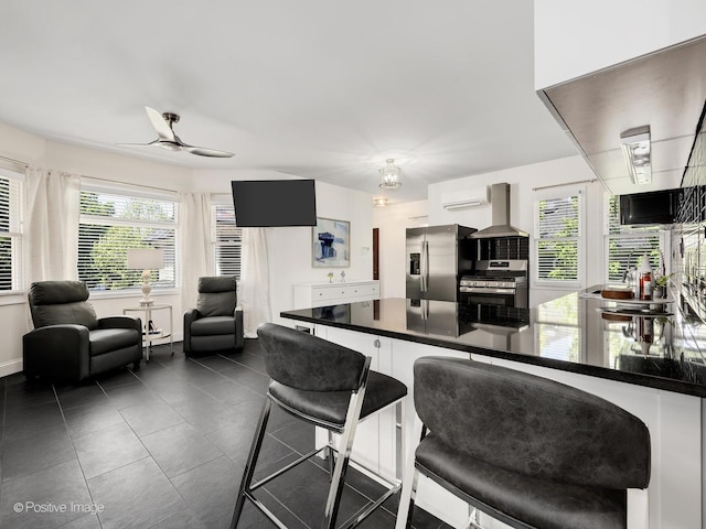213 S Ashland Ave, La Grange, IL 60525 - kitchen featuring stainless steel appliances, wall chimney range hood, a peninsula, dark countertops, and ceiling fan
