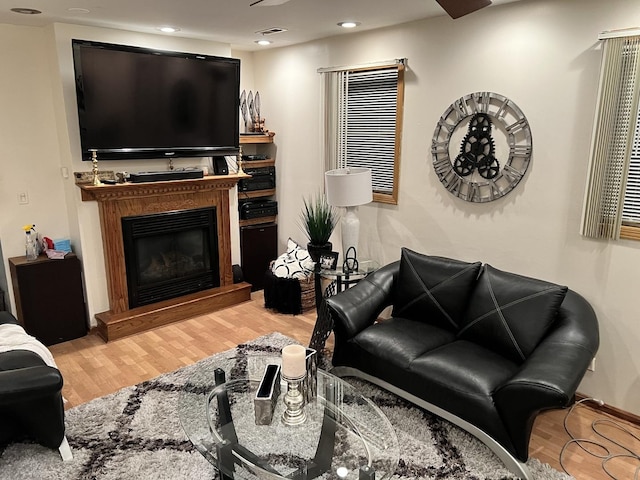 living area with visible vents, recessed lighting, a glass covered fireplace, and wood finished floors