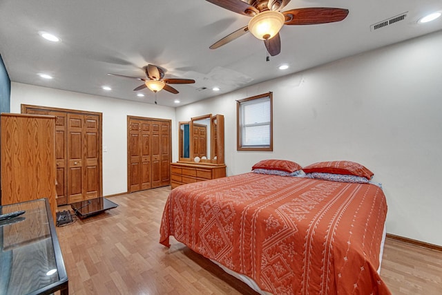 bedroom with visible vents, light wood-type flooring, baseboards, multiple closets, and recessed lighting