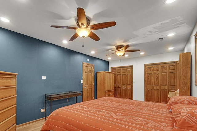 bedroom featuring visible vents, multiple closets, light wood-style floors, recessed lighting, and a ceiling fan
