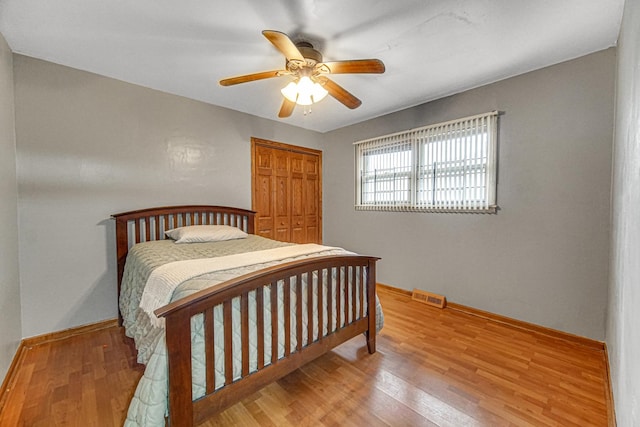 bedroom with baseboards, a closet, wood finished floors, and visible vents