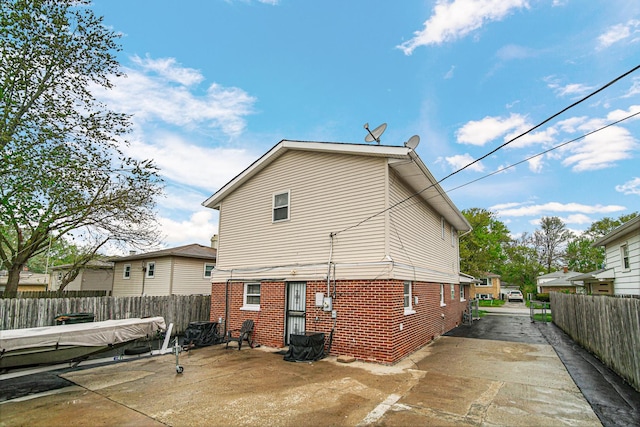 rear view of property featuring brick siding, a fenced backyard, a patio area, and concrete driveway