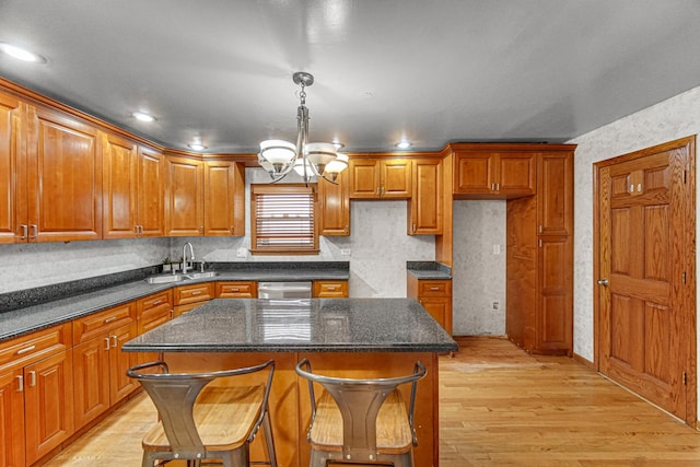 kitchen with a chandelier, brown cabinetry, light wood finished floors, and dishwasher