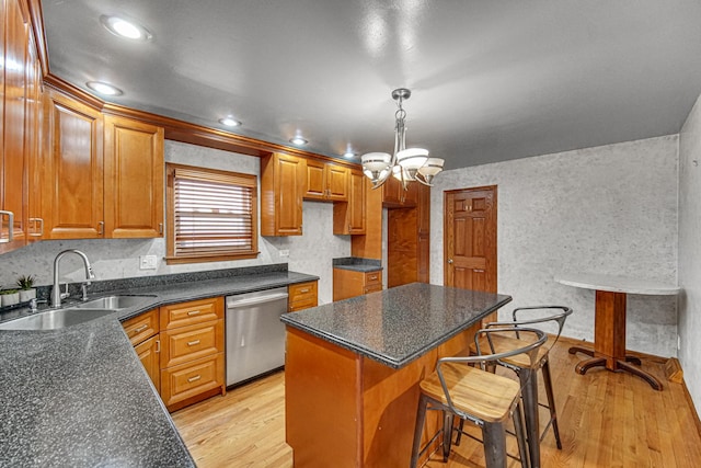 kitchen with a center island, stainless steel dishwasher, a sink, light wood-style floors, and a breakfast bar