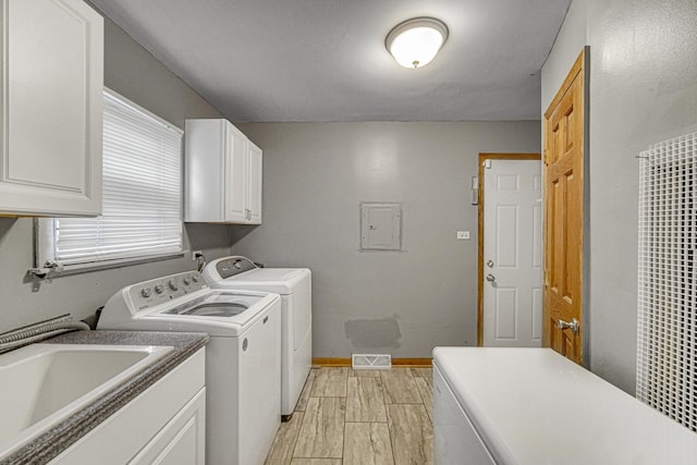 washroom featuring cabinet space, independent washer and dryer, a sink, baseboards, and visible vents