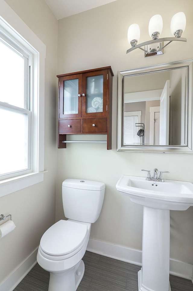 bathroom with baseboards, toilet, and a sink