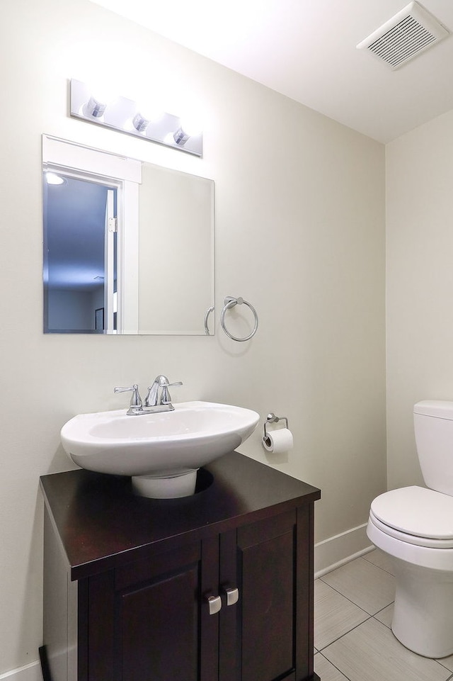 half bathroom featuring toilet, vanity, baseboards, and tile patterned flooring