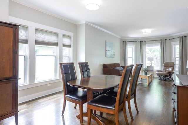dining room with wood finished floors, ornamental molding, and baseboards