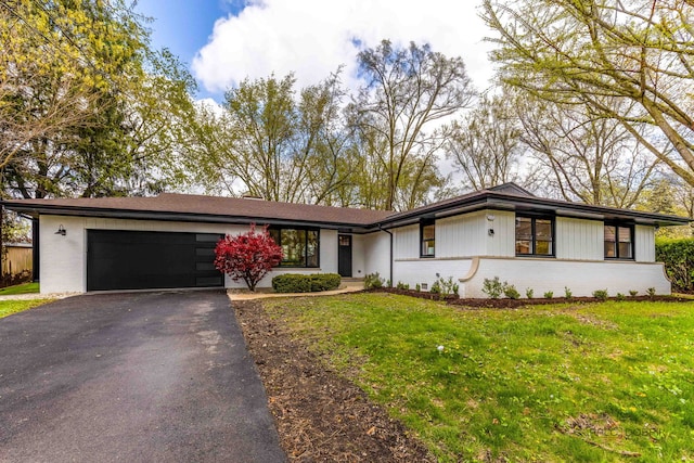 view of front of property featuring brick siding, an attached garage, a front lawn, and aphalt driveway
