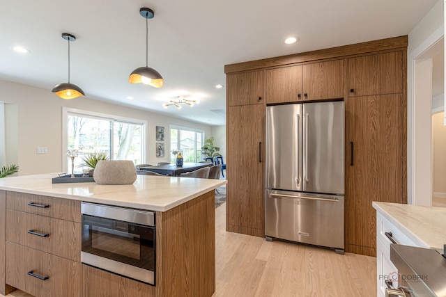 kitchen with light wood-style floors, recessed lighting, appliances with stainless steel finishes, and brown cabinets