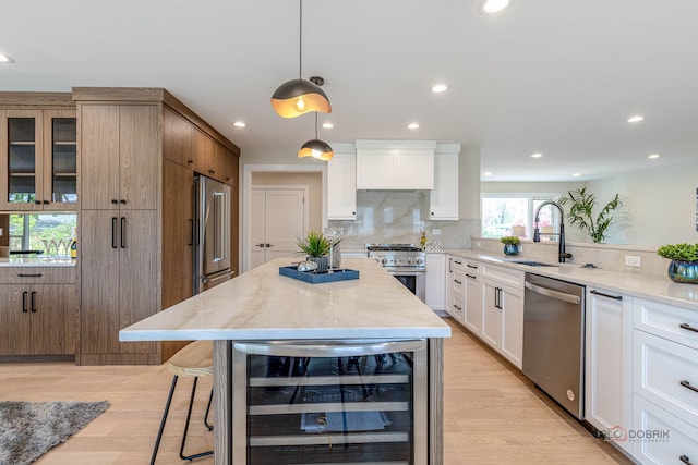 kitchen featuring decorative backsplash, light stone countertops, beverage cooler, high quality appliances, and a sink