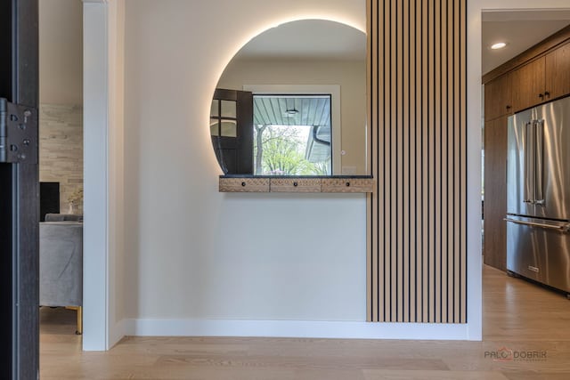corridor featuring arched walkways, baseboards, and light wood-type flooring