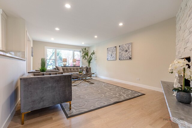 living area with recessed lighting, baseboards, wood finished floors, and a fireplace