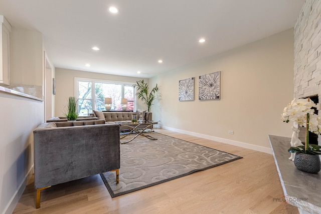 living area with baseboards, a fireplace, recessed lighting, and light wood-style flooring