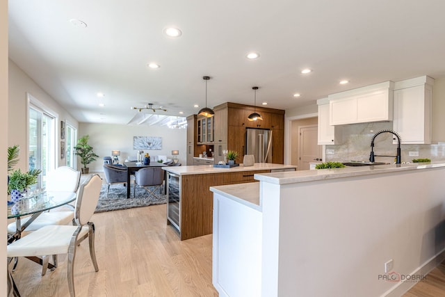 kitchen featuring a sink, light wood finished floors, a center island, backsplash, and high quality fridge