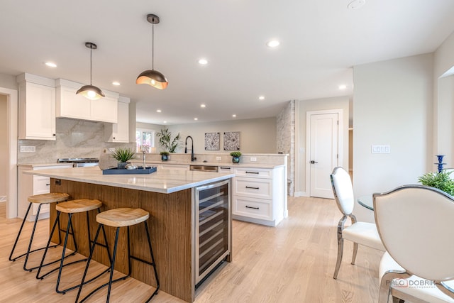 kitchen with a center island, white cabinetry, recessed lighting, light wood-type flooring, and wine cooler