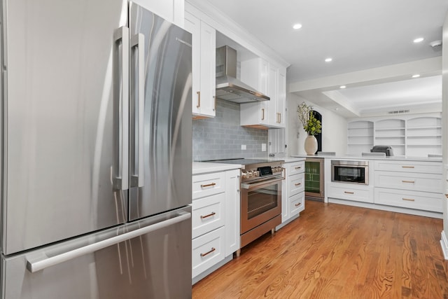 kitchen featuring wall chimney range hood, light countertops, beverage cooler, stainless steel appliances, and white cabinetry